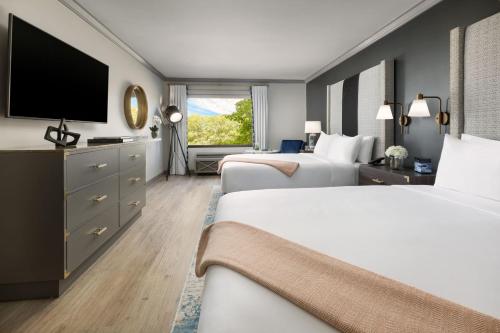 a hotel room with two beds and a flat screen tv at The Burgess Hotel, Atlanta, a Tribute Portfolio Hotel in Atlanta