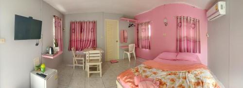 Dormitorio rosa con cama, mesa y sillas en Ban Suan Lung Rin en Kanchanaburi