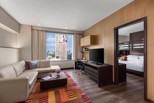 a living room with a couch and a bed and a mirror at Marriott Executive Apartments - Sukhumvit Park, Bangkok in Bangkok