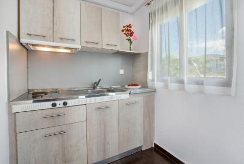 a kitchen with white cabinets and a sink and a window at Mani’s studios in Skala Sotiros