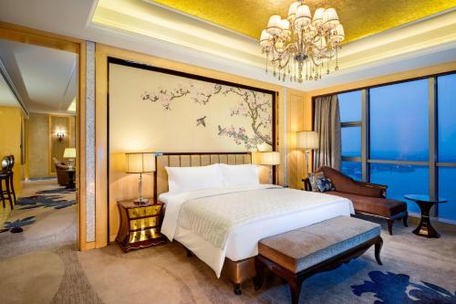 - une chambre avec un grand lit et un lustre dans l'établissement Le Méridien Yixing Hotel, à Yixing