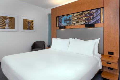 a bedroom with a large white bed and a chair at Aloft Asheville Downtown in Asheville