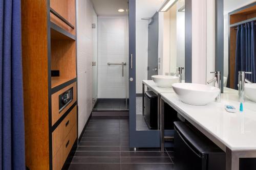 a bathroom with two sinks and a walk in shower at Aloft Asheville Downtown in Asheville