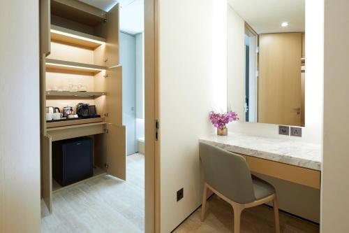 a bathroom with a vanity and a desk with a chair at Marriott Jeju Shinhwa World Hotel in Seogwipo