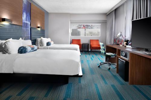 a hotel room with two beds and a flat screen tv at Aloft Nashville West End in Nashville