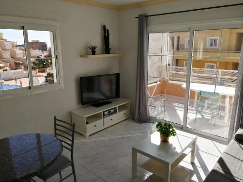 a living room with a flat screen tv and a table at Apartamento Costa Adeje - Orlando Complex in Adeje