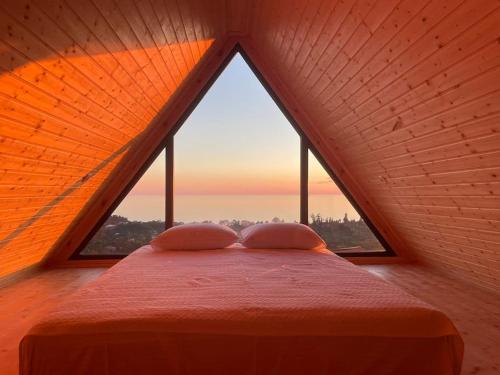 Beautiful Wooden house with seaside views في باتومي: سرير في غرفة مع نافذة كبيرة