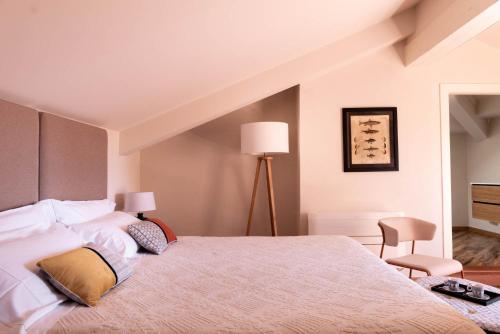 a bedroom with a large bed and a chair at Sella&Mosca Casa Villamarina in Alghero