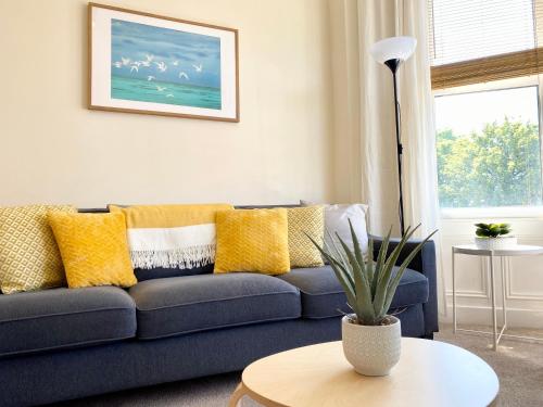 a living room with a blue couch with yellow pillows at 8 Margaret Road, Whitley Bay in Whitley Bay