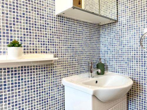 a bathroom with a sink and blue tiled walls at 8 Margaret Road, Whitley Bay in Whitley Bay