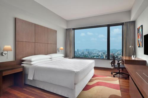 um quarto com uma cama branca e uma grande janela em Four Points by Sheraton Navi Mumbai, Vashi em Navi Mumbai