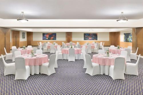 a room with white tables and white chairs and pink tables at Four Points by Sheraton Navi Mumbai, Vashi in Navi Mumbai