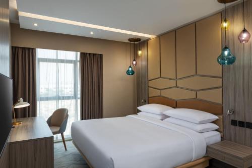 a bedroom with a large white bed and a desk at Four Points by Sheraton Production City, Dubai in Dubai