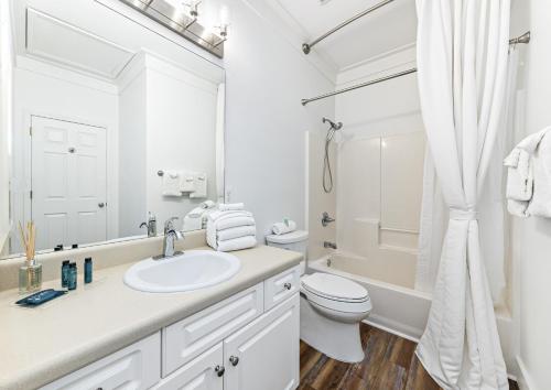 La salle de bains blanche est pourvue d'un lavabo et de toilettes. dans l'établissement Beach House steps to pool, Beach Access, à Gulf Shores