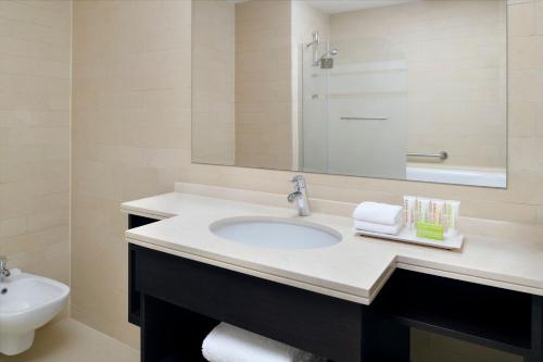 a bathroom with a sink and a mirror and a toilet at Le Meridien City Center Doha in Doha