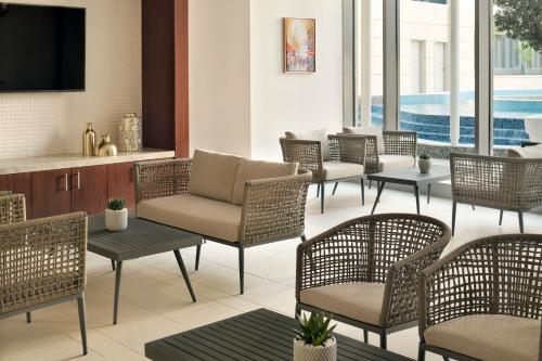 a lobby with chairs and tables and a television at Le Meridien City Center Doha in Doha