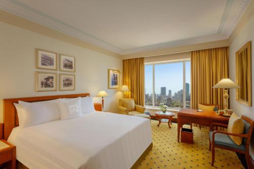 ムンバイにあるITC Grand Central, a Luxury Collection Hotel, Mumbaiのベッド、デスク、窓が備わるホテルルームです。
