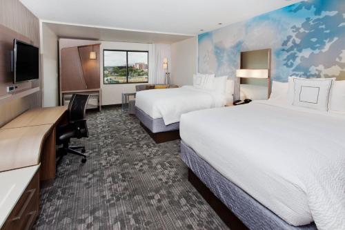 フェニックス・シティにあるCourtyard by Marriott Columbus Phenix Cityのベッド2台とデスクが備わるホテルルームです。