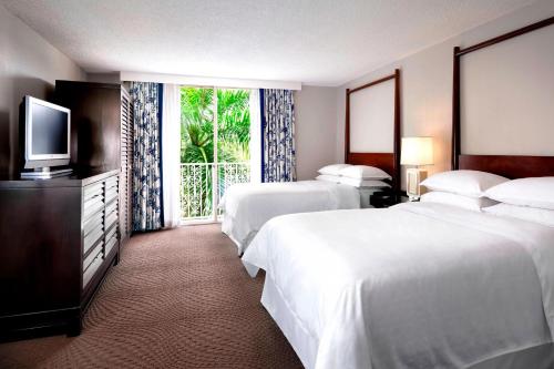 um quarto de hotel com duas camas e uma televisão em Sheraton Suites Fort Lauderdale at Cypress Creek em Fort Lauderdale