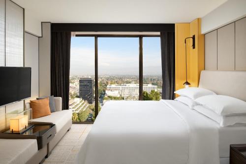 a bedroom with a large white bed and a large window at Sheraton Universal in Los Angeles