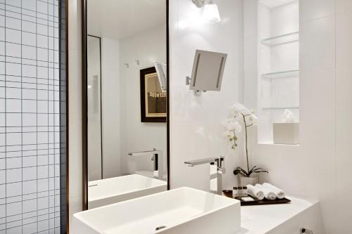 a white bathroom with a sink and a tub at Sheraton Universal in Los Angeles