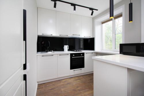 a white kitchen with white cabinets and a black oven at Новые великолепные апартаменты в центре, Желтоксан 159 in Almaty