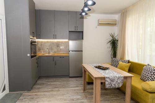a living room with a yellow couch and a table at Alagen Apartments Burgas in Burgas City