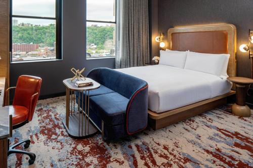 um quarto de hotel com uma cama e uma cadeira em The Industrialist Hotel, Pittsburgh, Autograph Collection em Pittsburgh