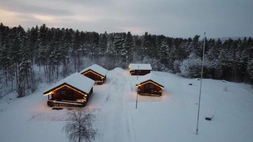 a group of lodges covered in snow with trees at Camping Fredrika-Braber in Fredrika