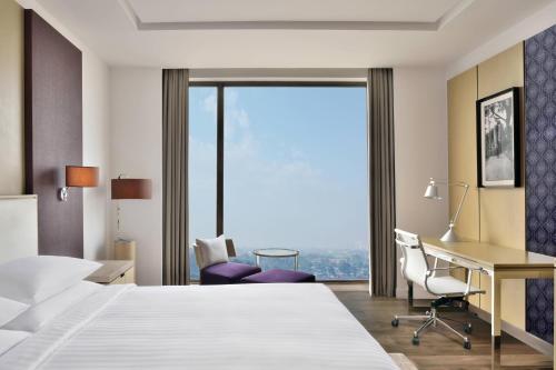 シリグリにあるCourtyard by Marriott Siliguriのベッド、デスク、窓が備わるホテルルームです。