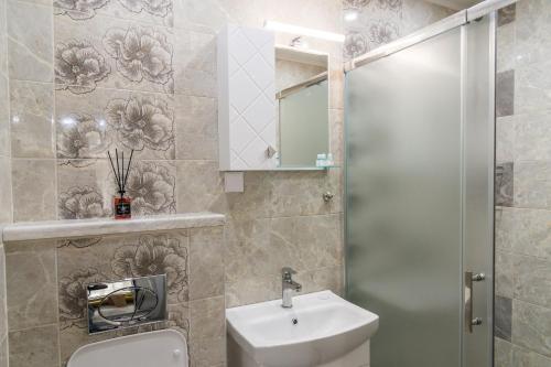a bathroom with a sink and a toilet and a mirror at Alagen Apartments Burgas in Burgas