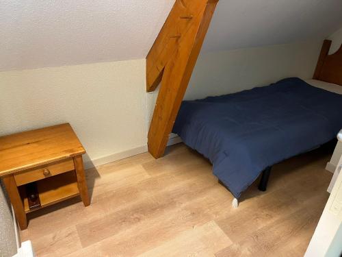 a small bedroom with a bed and a wooden table at Charmant T2 bis in Cauterets