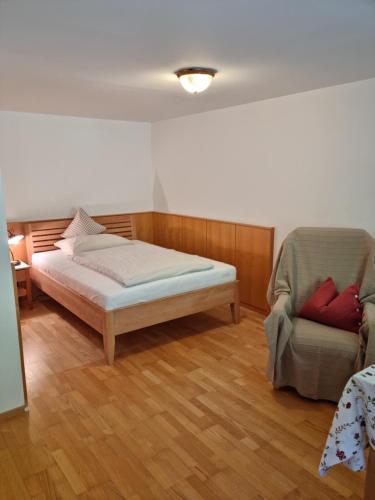 a bedroom with a bed and a chair at Pension Ladner in Grundlsee