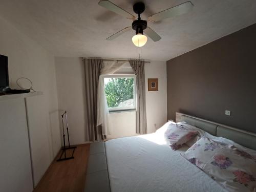 a bedroom with a bed with a ceiling fan and a window at Sonja Apartment in Premantura