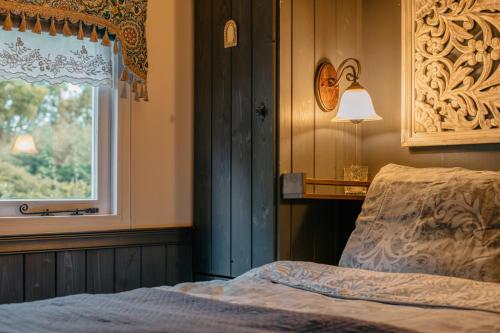 a bedroom with a bed and a window at Pipowagen de Zwerveling aan zee in Oostkapelle