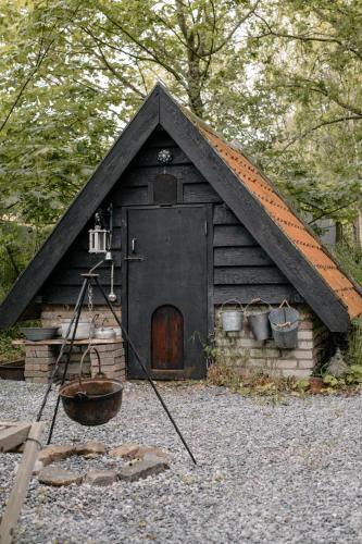 a small house with a black roof and a bucket at Pipowagen de Zwerveling aan zee in Oostkapelle