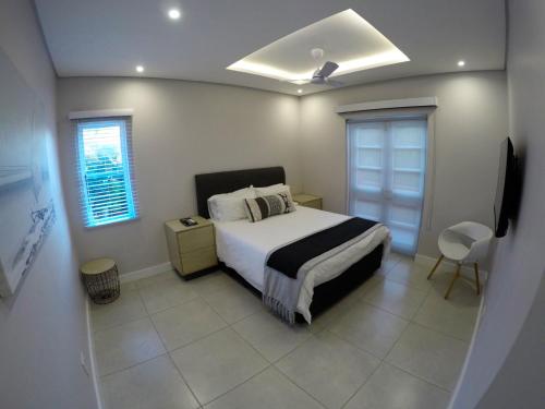 a bedroom with a bed and a window and a television at Stylish Sea View Apartment in Santorini Estate. in Ballito