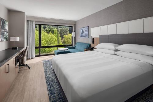 una camera con un grande letto bianco e una sedia blu di Pleasanton Marriott a Pleasanton