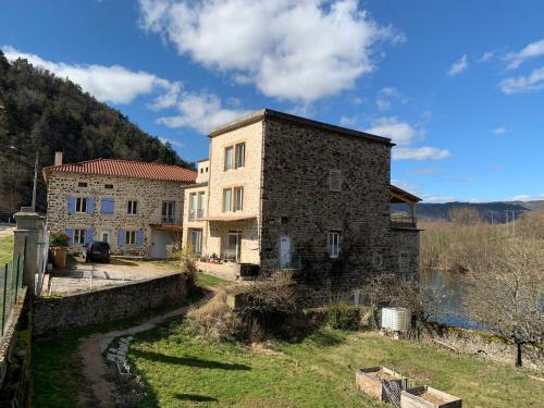 - un vieux bâtiment en pierre à côté d'une étendue d'eau dans l'établissement Gite moulin de la ribeyre, à Saint-Vincent