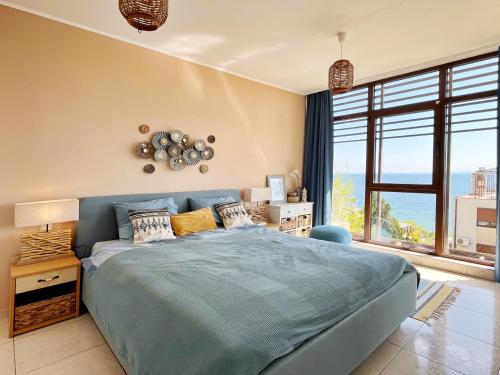 a bedroom with a blue bed and a large window at Dolce Vita Blue Boho, Premium Apartment with seaview in Sveti Vlas