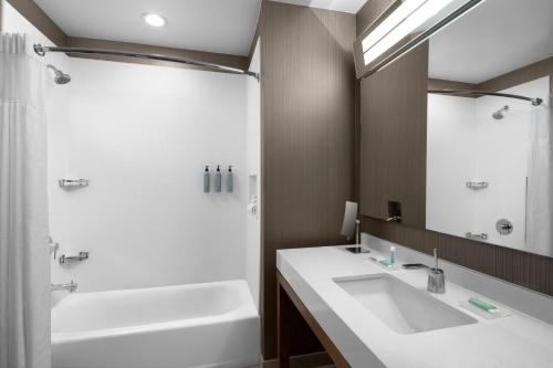 a bathroom with a tub and a sink and a shower at Courtyard by Marriott Salt Lake City Cottonwood in Cottonwood Heights