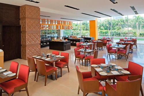 a restaurant with wooden tables and red chairs at Fairfield by Marriott Lucknow in Lucknow