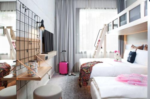a hotel room with two beds and a pink suitcase at Moxy Rust in Rust
