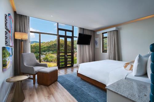 una camera d'albergo con un letto e una grande finestra di The BRIX Autograph Collection a Port-of-Spain