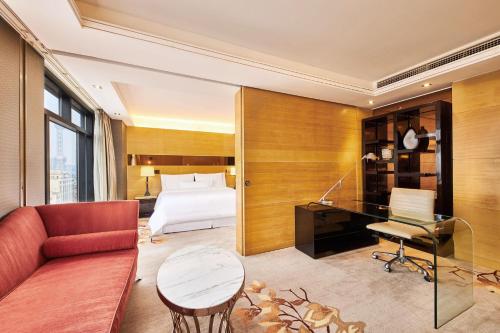 a hotel room with a bed and a couch and a desk at The Westin Bund Center, Shanghai in Shanghai