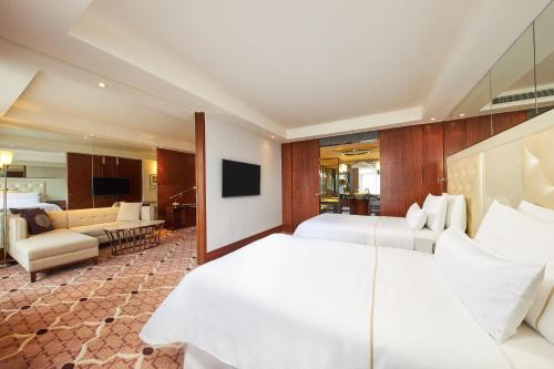 a hotel room with two beds and a living room at The Westin Bund Center, Shanghai in Shanghai