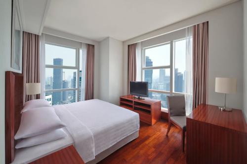 a bedroom with a bed and a desk with a television at The Mayflower, Jakarta-Marriott Executive Apartments in Jakarta