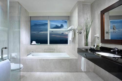 a bathroom with a tub and a sink and a window at The Mayflower, Jakarta-Marriott Executive Apartments in Jakarta