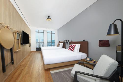 une chambre d'hôtel avec un lit et une chaise dans l'établissement Moxy Shanghai Xuhui, à Shanghai