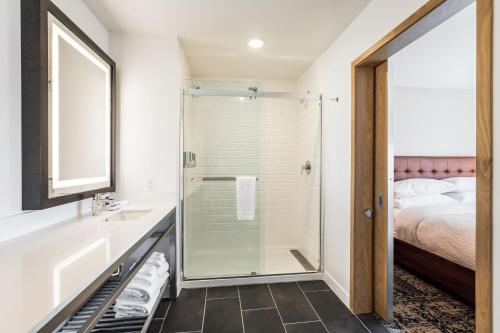 a bathroom with a glass shower and a bed at Four Points by Sheraton Elkhart in Elkhart
